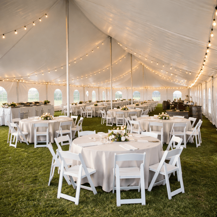 Elegant event tent setup with tables, chairs, and string lights