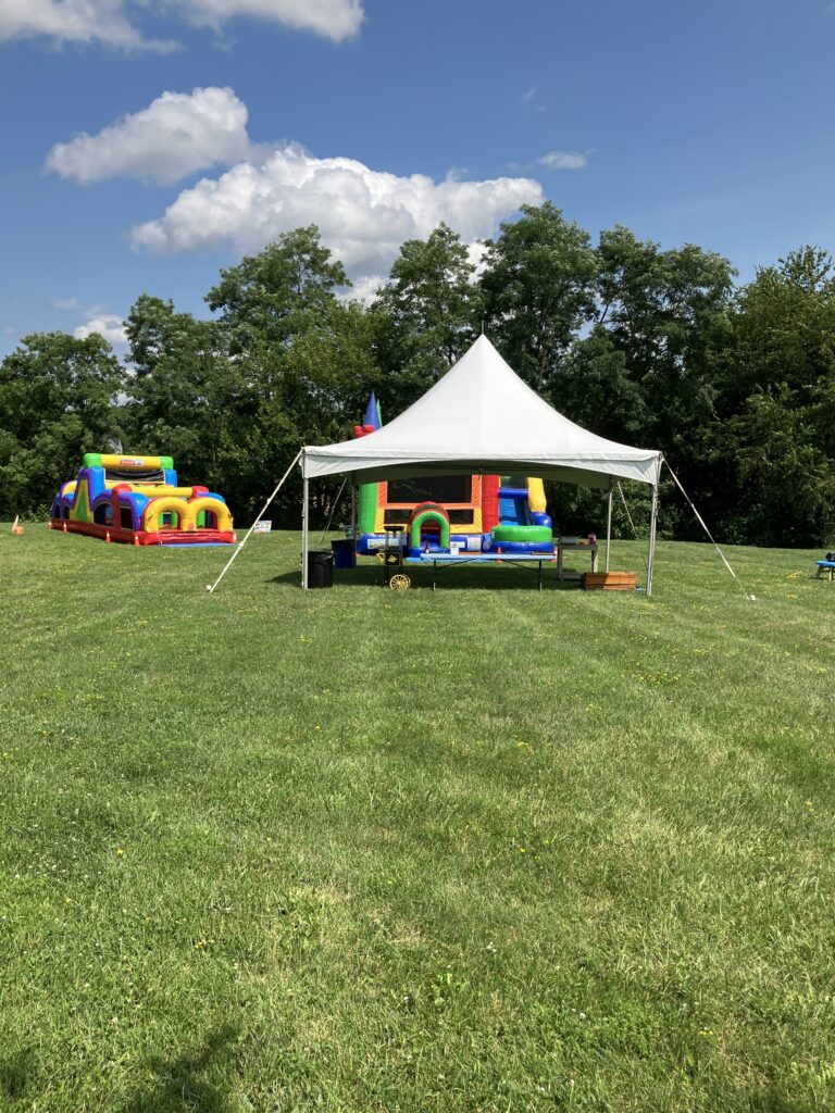 Tent rental setup with bounce houses at an outdoor event
