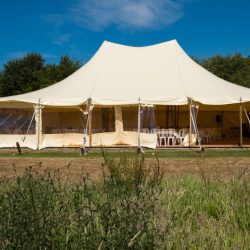 Large white pole tent setup for outdoor wedding or event rental