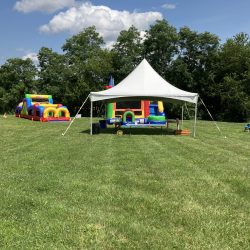 Tent rental setup with bounce houses at an outdoor event